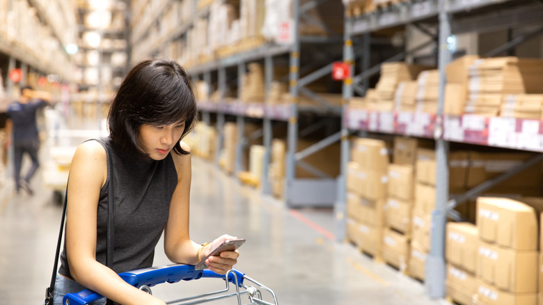 A person checking her phone while shopping in an IKEA warehouse
