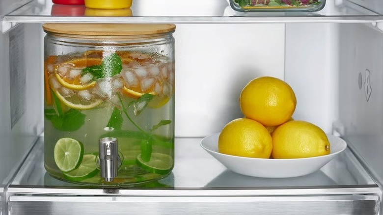 An IKEA beverage dispenser filled with infused water on a fridge shelf