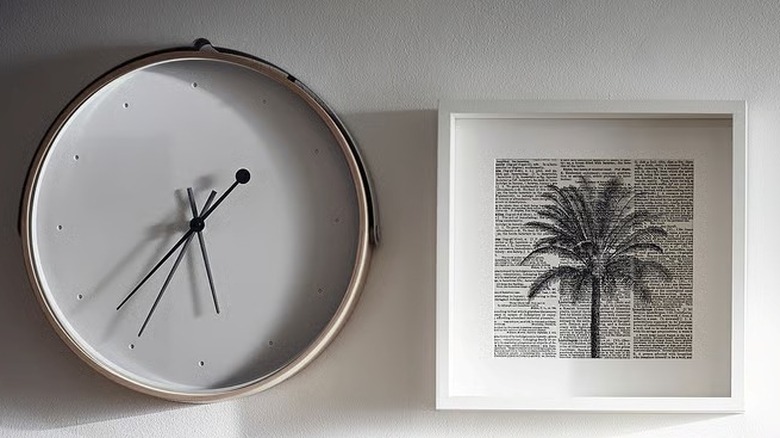IKEA's ROTBLÖTA wall clock on a wall next to a palm tree print