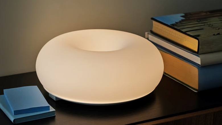 An IKEA VARMBLIXT lamp on a table next to books