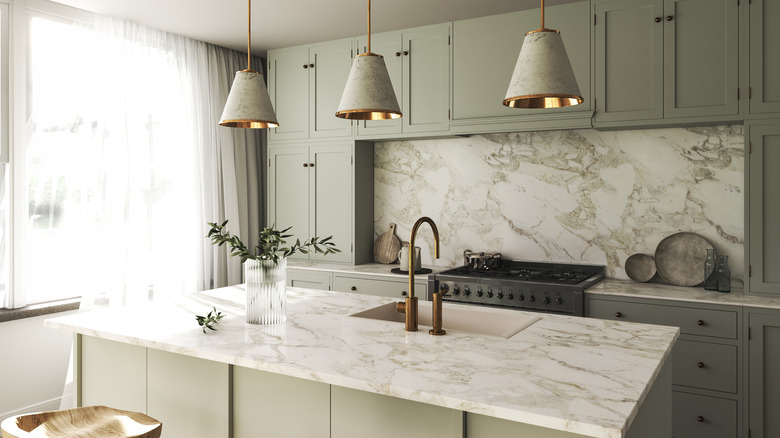 Light kitchen with green cabinets and warm marble countertops