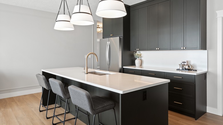 Black and white kitchen with white quartz countertops and black cabinets
