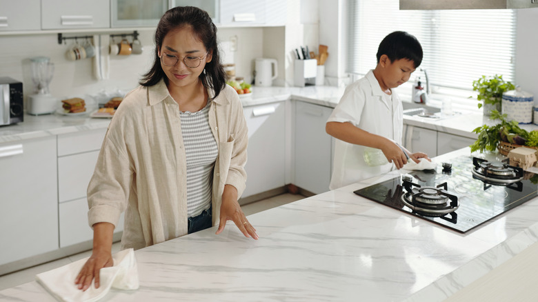 Woman wiping down a marble countertop with a cloth