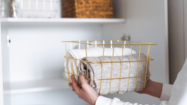 Person putting a decorative wire storage bin on a shelf