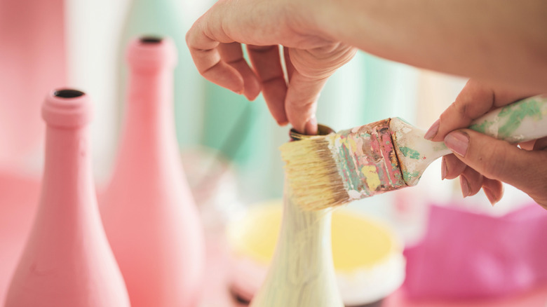 person painting wine bottles