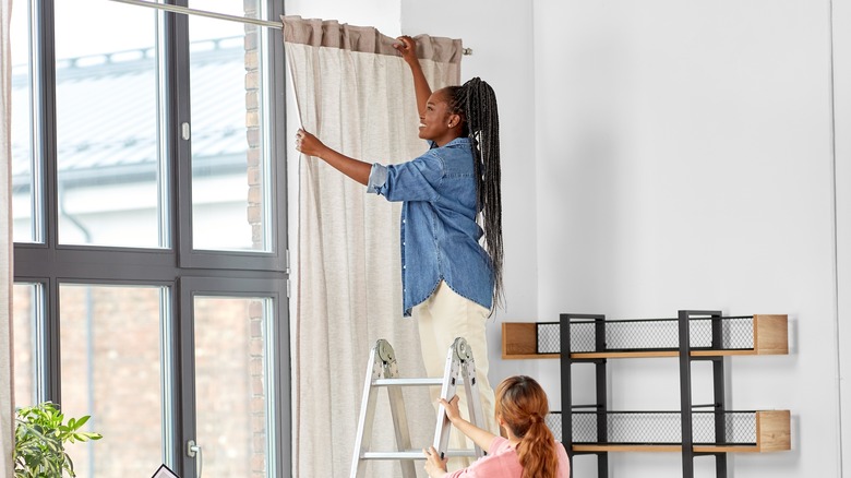 woman removing curtains from window