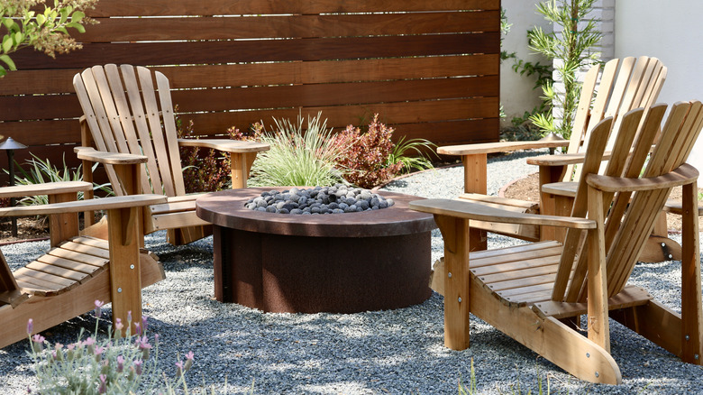 Wooden chairs around outdoor fireplace on gravel patio