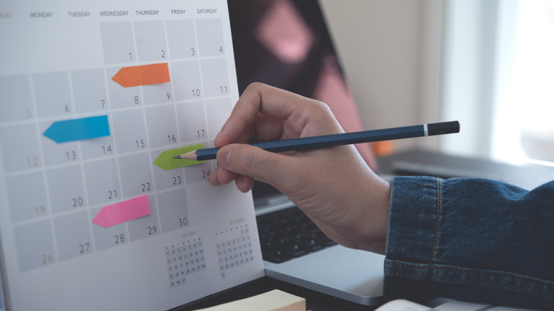 Person writing dates on a calendar