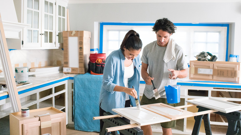 Couple painting cabinets to make cosmetic updates to kitchen