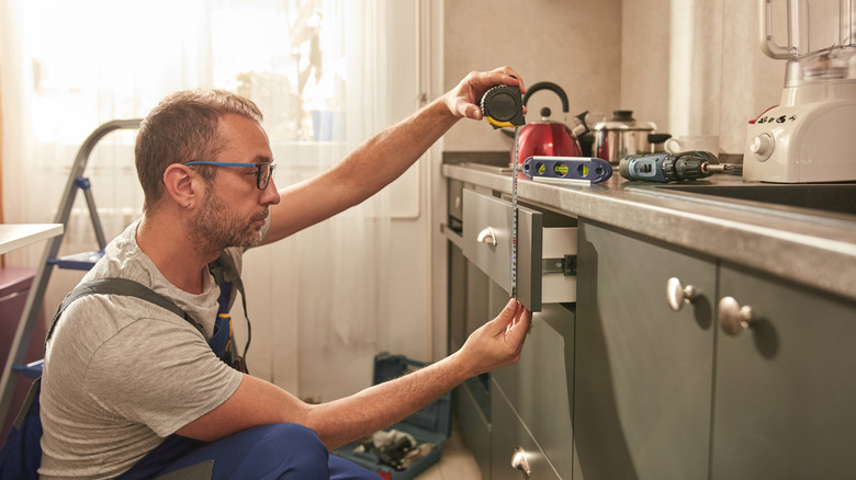 Man taking measurements of kitchen drawer