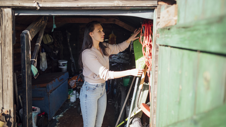 Woman organizing yard tools in a backyard shed