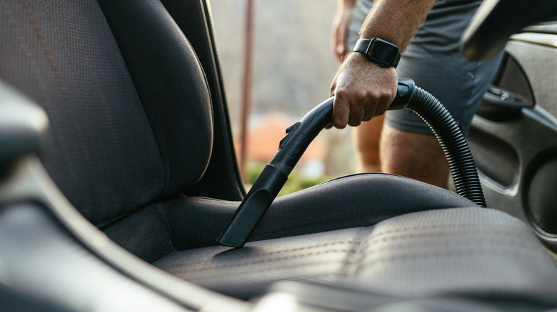 Person vacuuming out the interior of a car