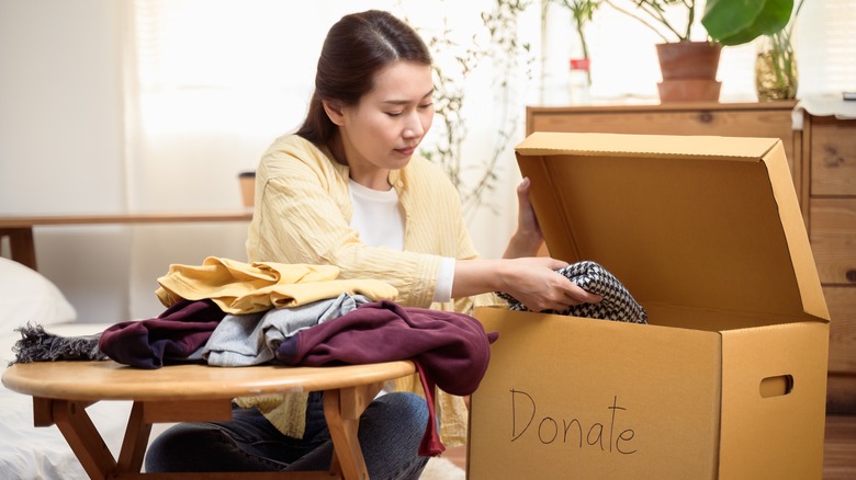 Person putting items in a box to donate after decluttering
