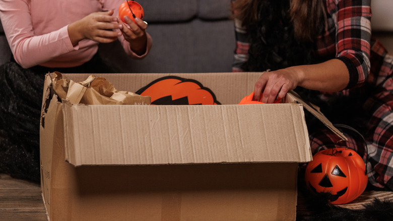Two people going through Halloween decorations in a box