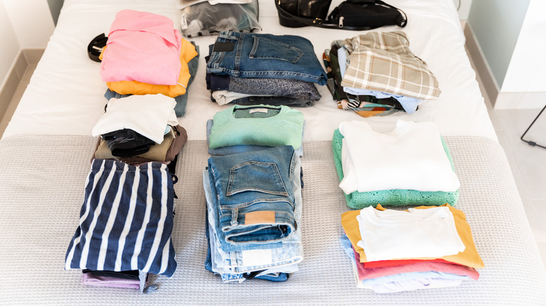Piles of folded clothes on a bed