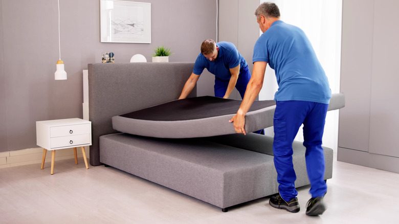 Two men moving a mattress out of bed frame