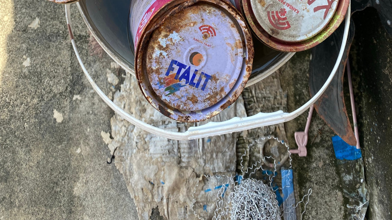Rusted old cans of paint in a bucket