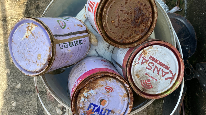 Rusted old cans of paint in a bucket
