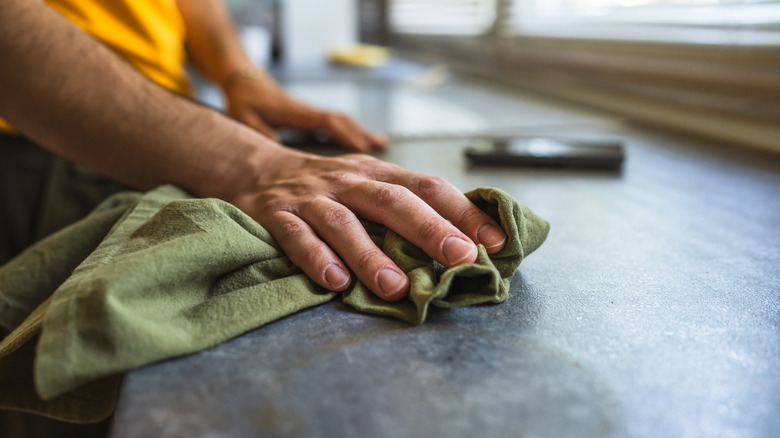 Man cleaning a countertop with a green cloth