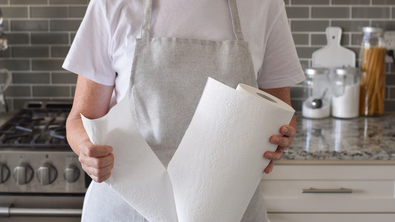 Person in apron pulling paper towel off roll