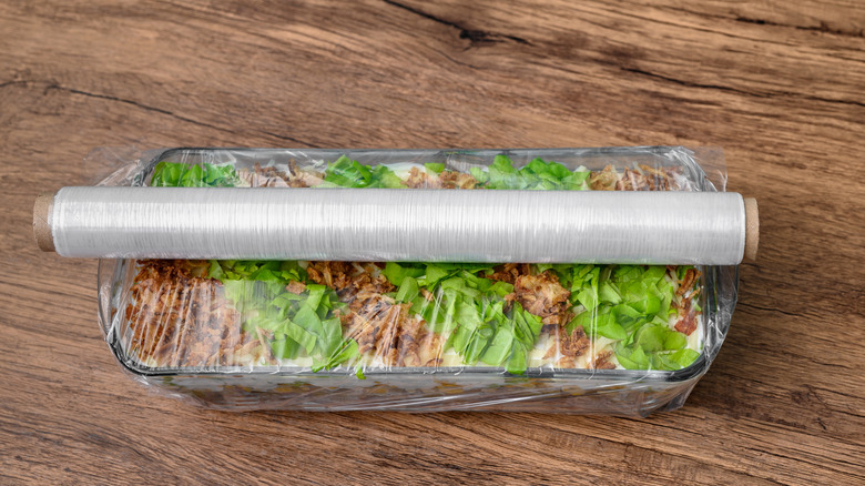 Roll of plastic wrap around glass pan of food