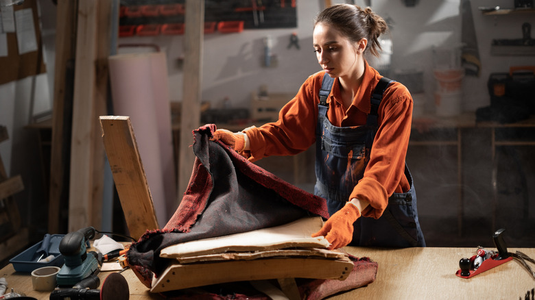 A woman reupholstering a red chair