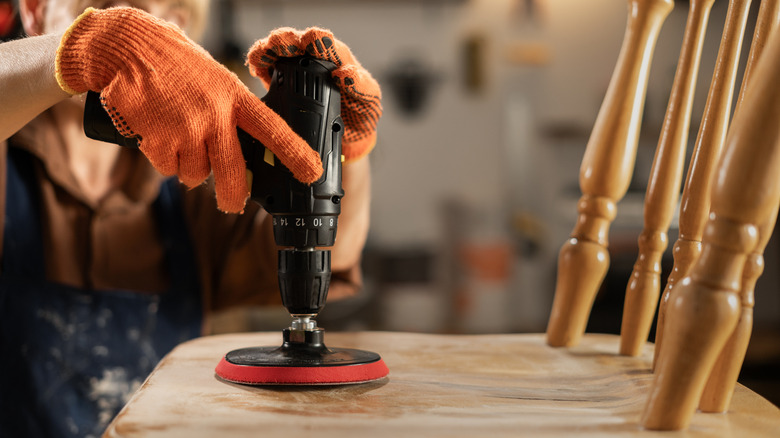 Person using a power sander on a chair