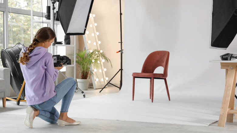 A woman taking a picture of a chair in a studio