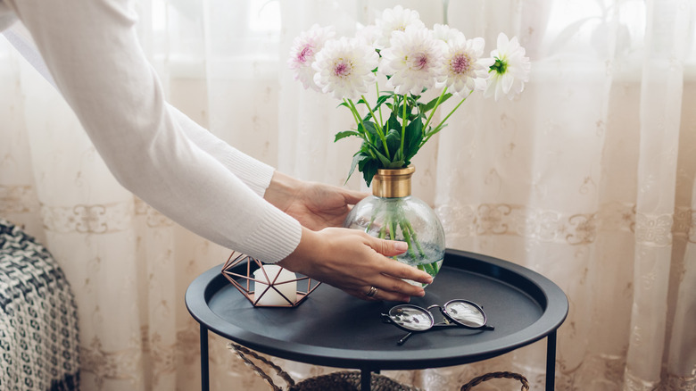 Person putting a vase on a black table holding glasses