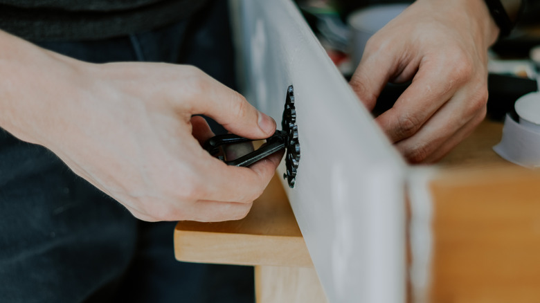 A person installing black hardware on a drawer