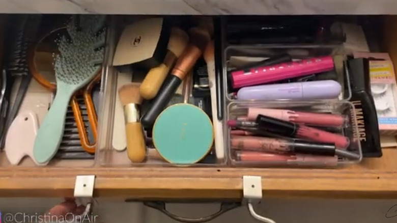 Makeup organized in clear containers in an open bathroom drawer