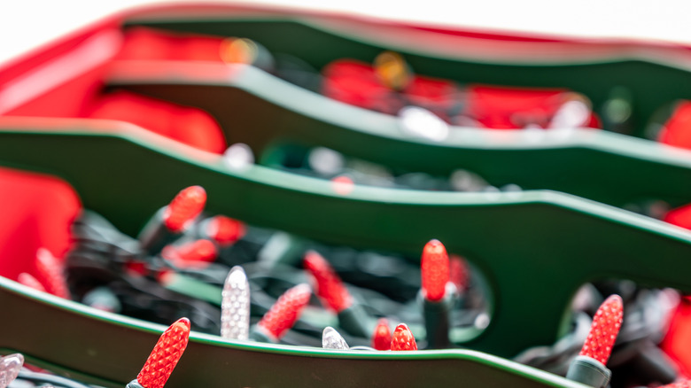 Strands of Christmas lights wrapped around holders and placed in a storage bin