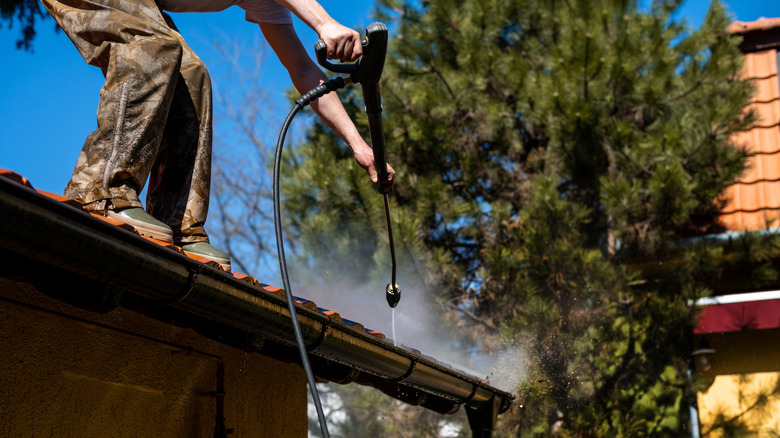 worker cleaning gutters with tool