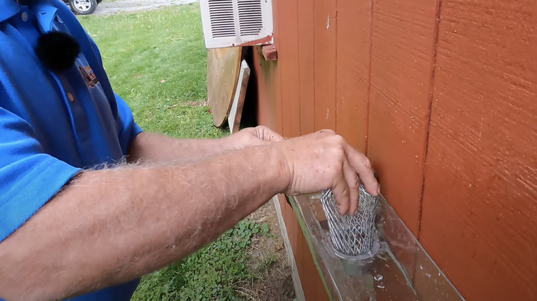 person demonstrating downspout strainer installation
