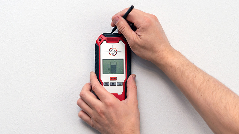 man using stud finder on wall