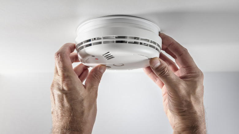 Person testing a smoke alarm attached to the ceiling