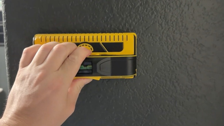 Person using Franklin Sensors Prosensor M210 Stud Finder on wall