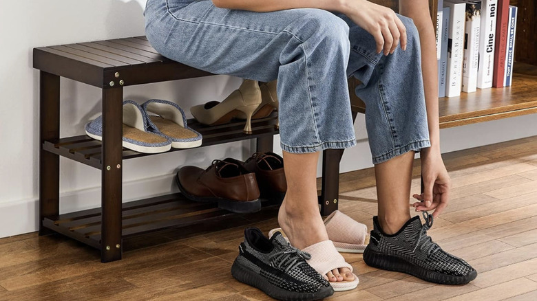 Woman sitting on Pipishell Bamboo Shoe Rack Bench, switching shoes