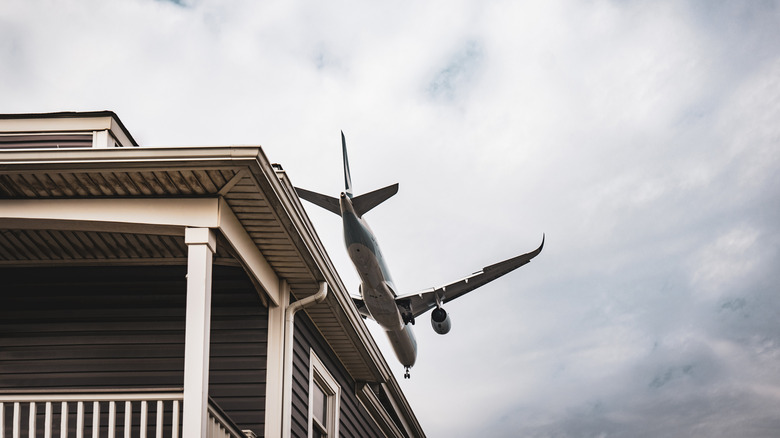Aircraft flying very low, close to the roof of a house.