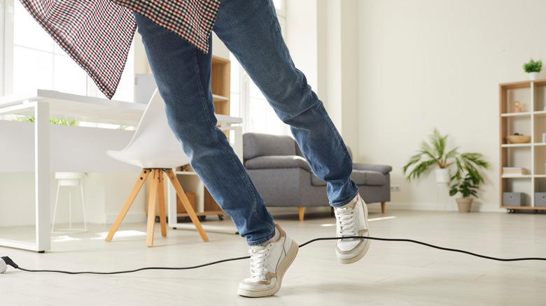 A person tripping over a cord in the living room.
