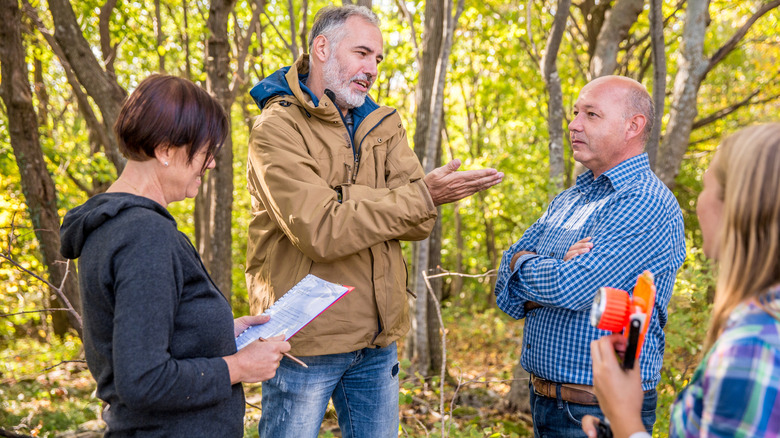 Surveyor and land owners fighting about property lines in a forested area.