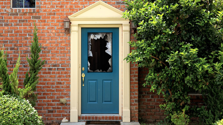 Broken glass in a blue, front door window.