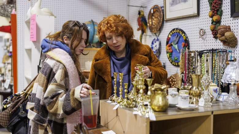 Two women inspect objects at thrift store