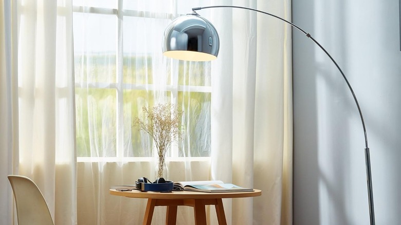 Arquer floor lamp next to table and chair