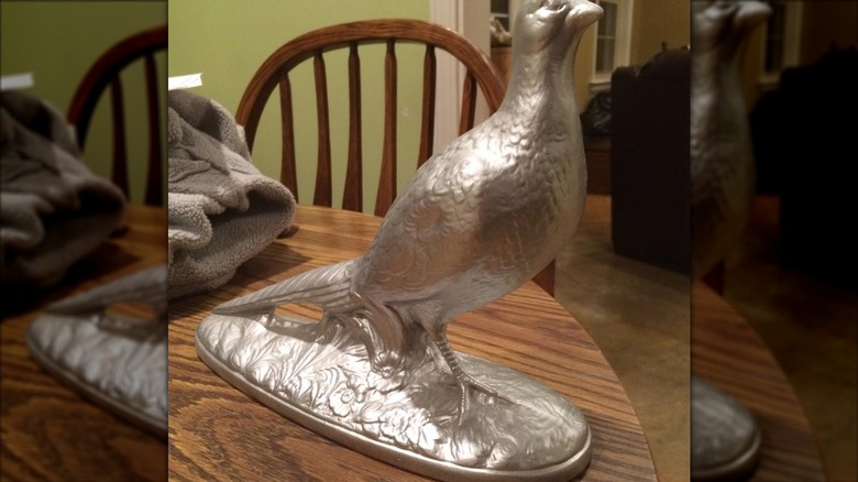 silver painted bird statue on table