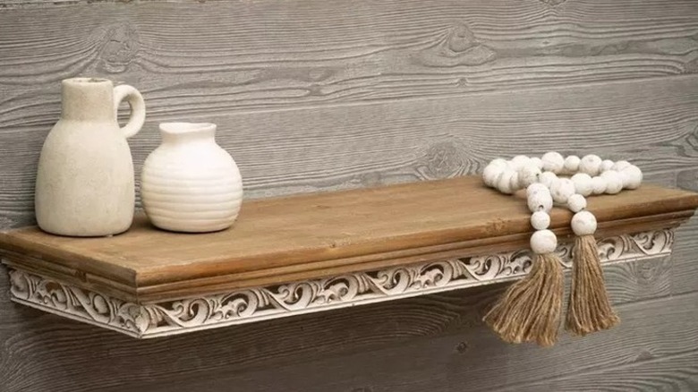 Wooden floating shelf with white decor on top