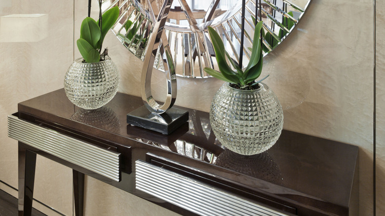 decorative table with large mirror above it and glass vases on it