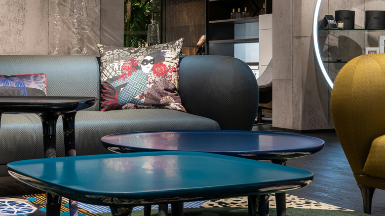 retro room with two textured sofas with different colors, throw pillows, and three reflective coffee tables