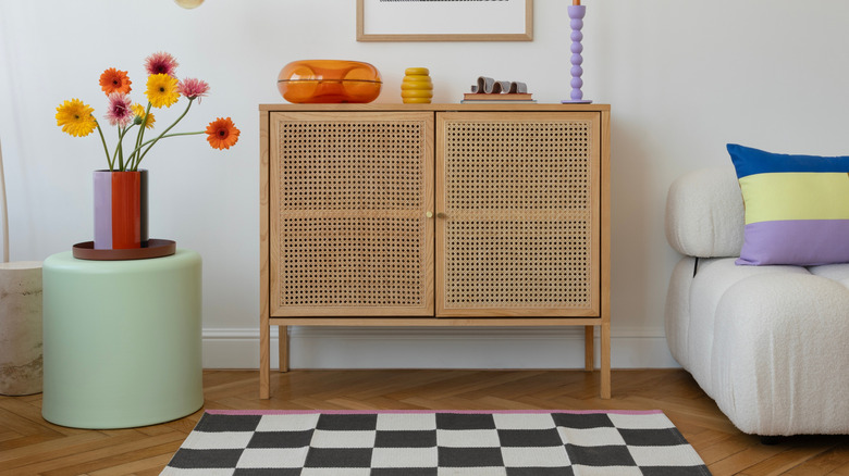 rattan cabinet beside bold colored furniture