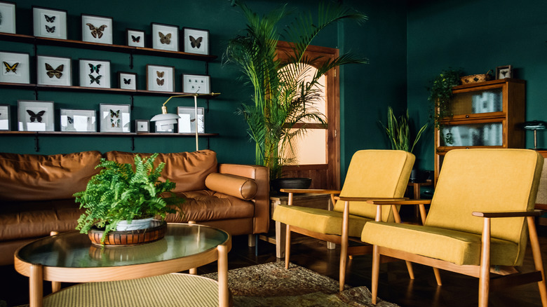 living room with two yellow chairs, a sofa and coffee table, rug, and tropical-looking plants